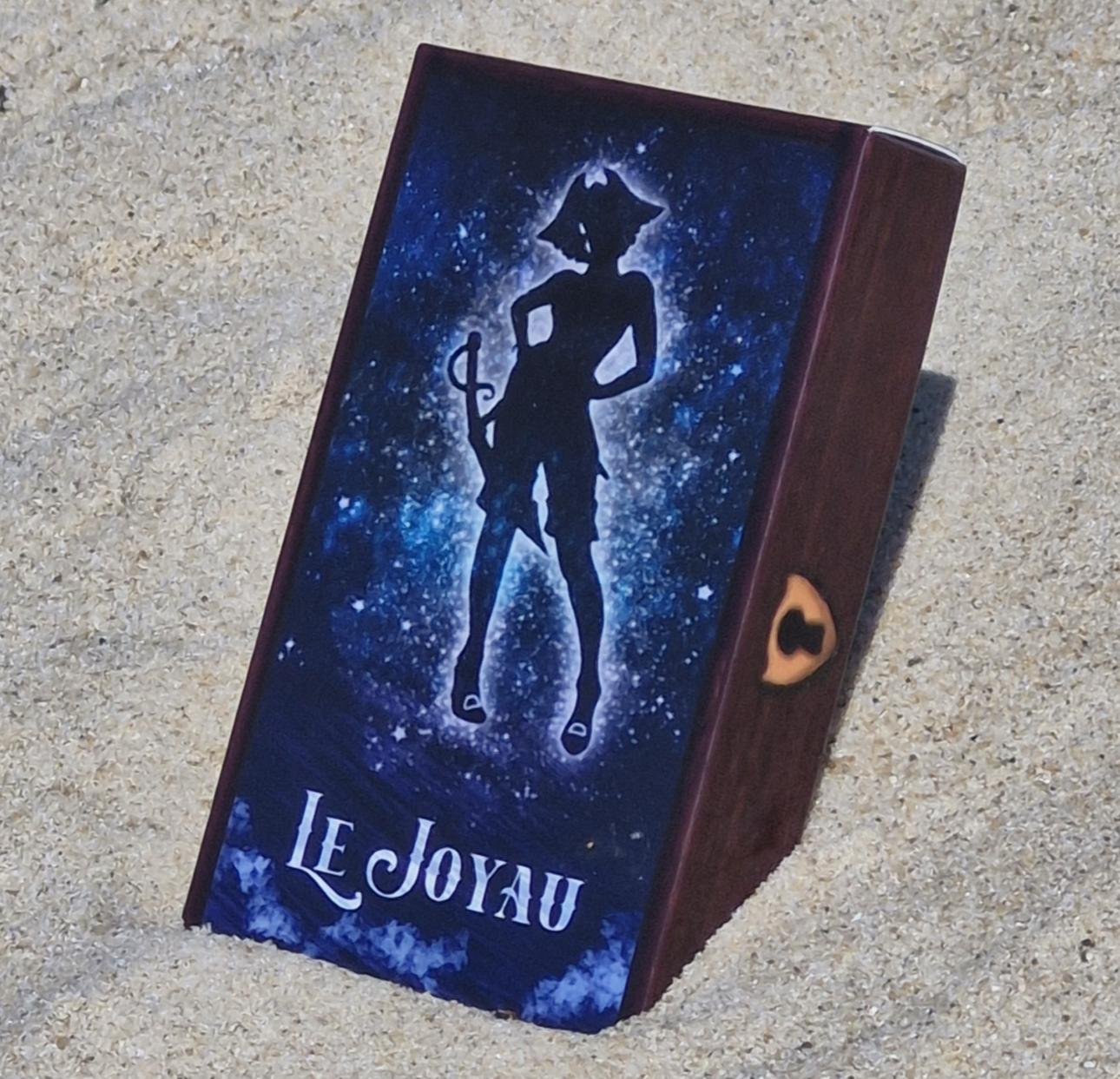 La boite du jeu Le Joyau de 54 femmes marins est dans le sable, il semble comme un coffre au trésor